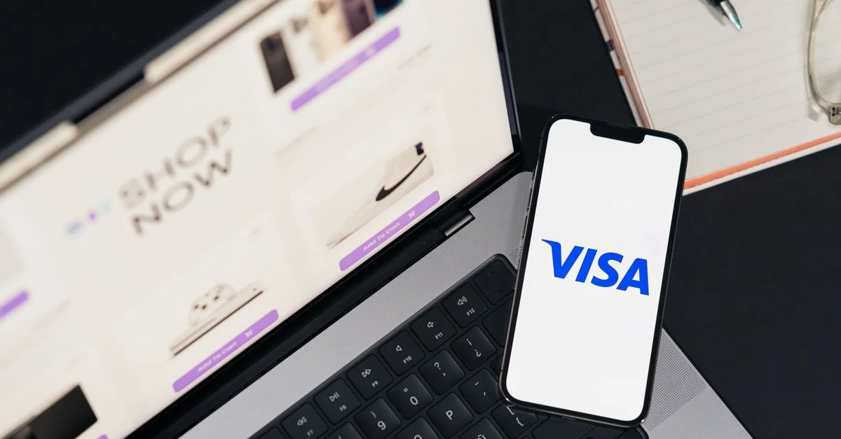 Smartphone affichant VISA sur un ordinateur portable pour une expérience de shopping en ligne.