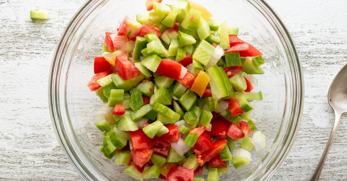Vue de dessus d'une salade de légumes frais avec des concombres et des tomates dans un bol en verre sur une table.