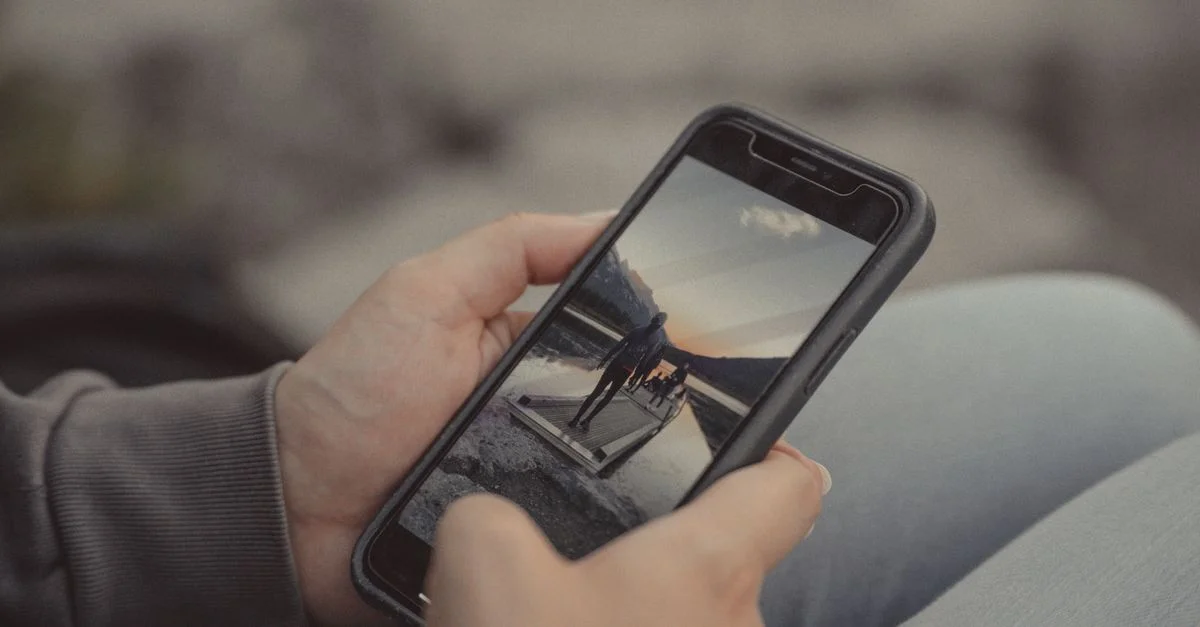 Gros plan de mains tenant un smartphone montrant une scène de montagne, capturée en extérieur à Banff.