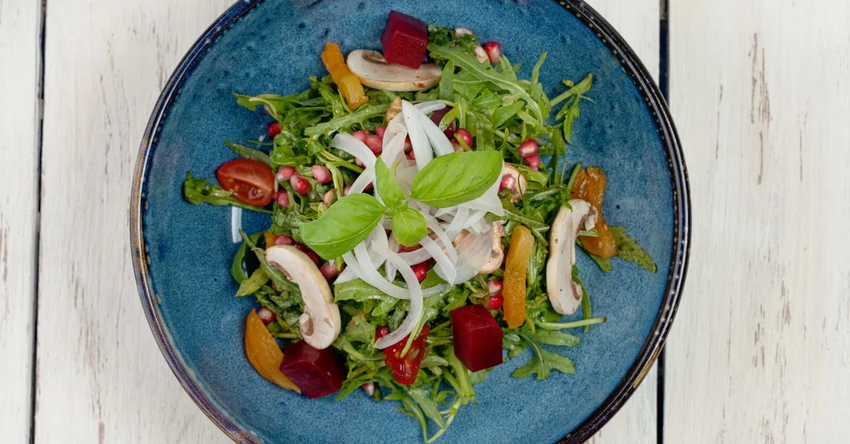 Vue de dessus d'une salade de légumes colorée avec des champignons, des tomates et de la roquette, parfaite pour les régimes soucieux de la santé.